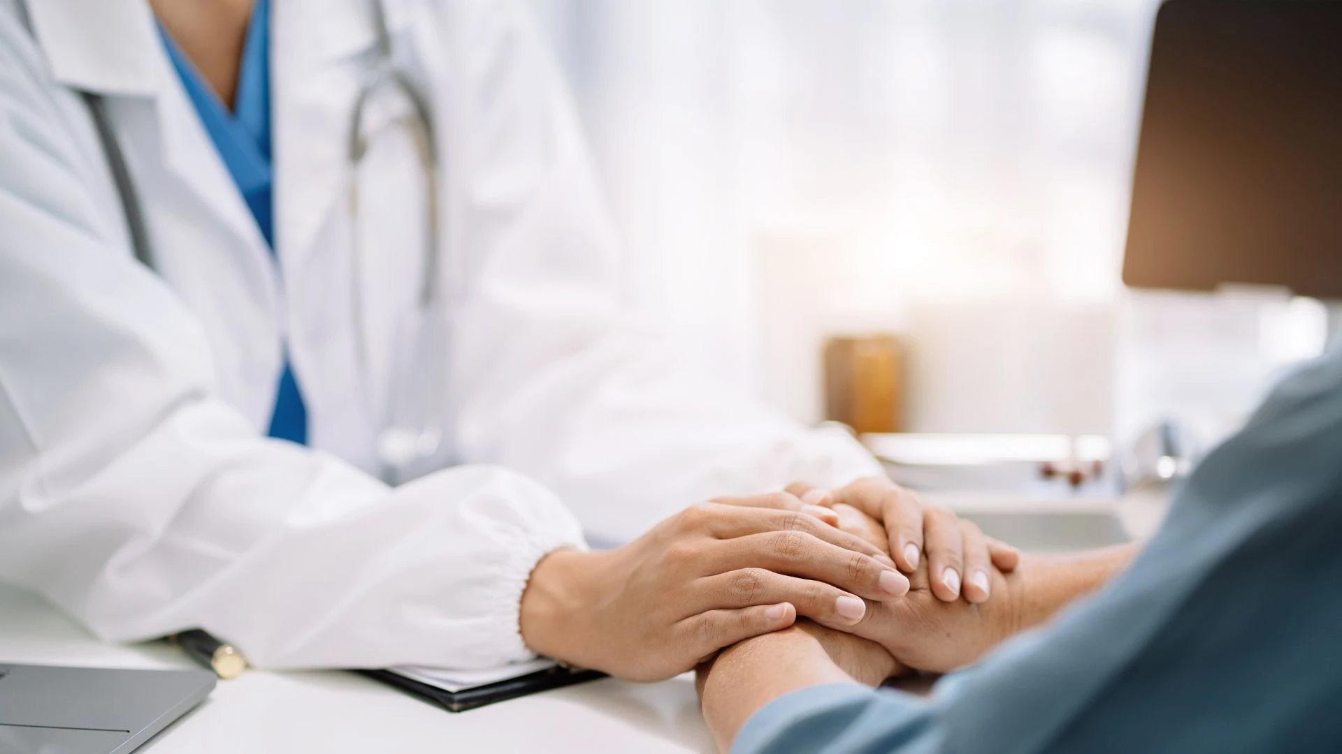 Physician comforting a patient by gently holding their hands, promoting support and trust.